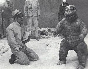 아리카와 사다마사가 난쟁이 마치안(미니라)에게 지시를 내리고 있다. "난쟁이 마치안"은 두꺼운 고무 의상 안에서 롤과 플립을 수행하는 능력 때문에 부분적으로 배역되었다.