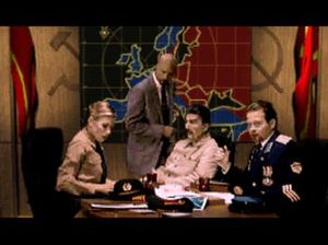 케인(서 있는 모습)이 이오시프 스탈린(중앙)과 나디아(왼쪽), 그라덴코(오른쪽)에게 조언한다.