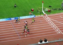 Eight men approach the finishing line of race at a stadium track