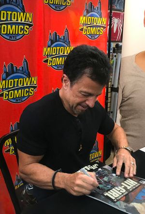 아티스트 존 로미타 주니어가 맨해튼의 미드타운 코믹스에서 시리즈 사본에 서명하고 있다.