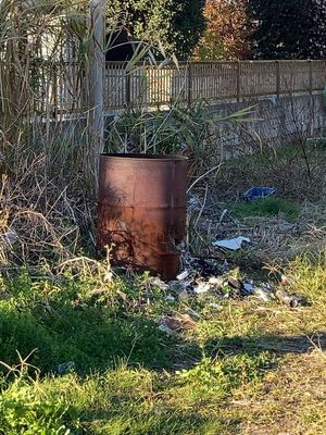 주택 정원에 놓인 드럼통. 쓰레기가 태워지고, 긁어낸 재와 쓰레기가 보인다.