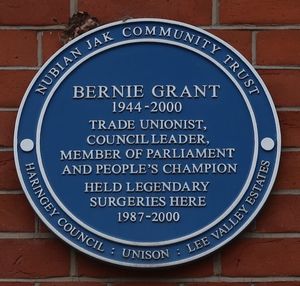 Blue plaque reading: "Bernie Grant 1944–2000 Trade Unionist, Council Leader, Member of Parliament and People's Champion held legendary surgeries here 1987–2000". Inscribed around the border is: "Nubian Jak Community Trust / Haringey Council / Unison / Lee Valley Estates"