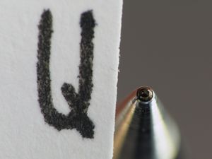 롤러볼 펜의 팁을 확대한 사진과 롤러볼 펜으로 쓴 글씨