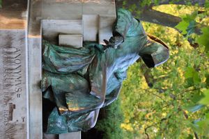 얼굴을 가린 후드를 쓴 남자가 벤치에 앉아 있다