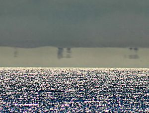 파타 모르가나가 멀리 떨어진 배들의 이미지를 알아볼 수 없도록 왜곡하고 있다