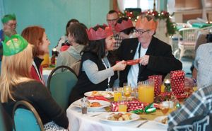 만찬에 참석한 사람들이 크래커를 잡아당기고 있다