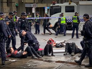 한 법 집행관이 서로 쇠사슬로 묶인 시위대의 쇠사슬을 자르기 위해 노력하고 있다.