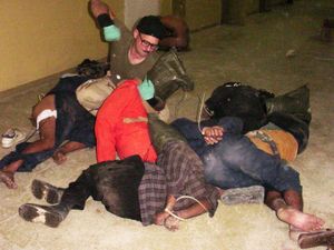 수갑을 찬 이라크 수감자들을 주먹으로 치는 찰스 A. 그래너.