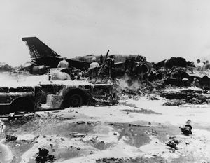 화재 이후 소화용 거품으로 둘러싸인 파괴된 갑판 트랙터와 RA-5C 항공기.