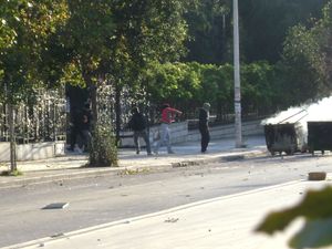 테살로니키 아리스토텔레스 대학교에 돌을 던지는 시위대와 불타는 쓰레기통에서 나오는 연기.