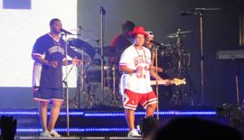 두 남자가 악기를 연주하고 두 명이 마이크에 대고 노래하는 사진