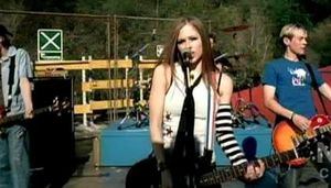 뮤직 비디오 속 라빈 - 넥타이, 척 테일러 올스타와 스케이터 의상을 착용하고 있다.