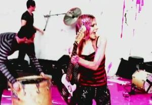 라빈과 밴드가 스튜디오에서 분홍색 페인트를 맞으며 악기를 부수고 있다.