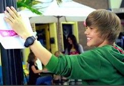 한 소년이 배경에 야외 레스토랑 장면이 있는 기둥에 표지판을 걸고 있다