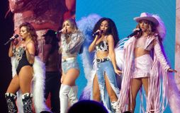 분홍색과 파란색 배경 앞에서 무대에 있는 젊은 여성 4명.