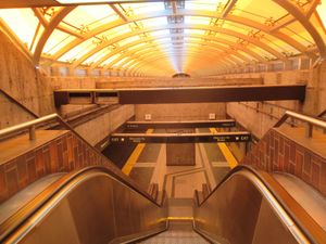 플랫폼, 중간 컨코스, 그리고 거리 레벨 사이의 에스컬레이터로, 모두 유리 지붕 아래에 있으며, 예술 작품 Joy가 있다.