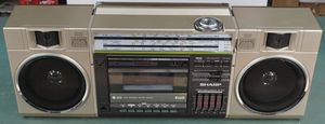 커색이 머리 위로 들고 있는 Sharp GF-7600 붐박스