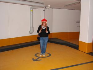 전통적인 검은 숲 모자를 쓴 여성이 주차 공간에 주차하고 있다.