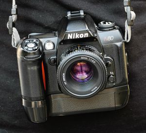 MB-16 배터리 그립과 Nikkor AF 50mm f/1.8D 렌즈를 장착한 검은색 니콘 F80 (N80)