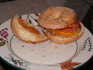 완전히 익힌 달걀 프라이, 베이컨, 치즈를 참깨 베이글에 넣은 것