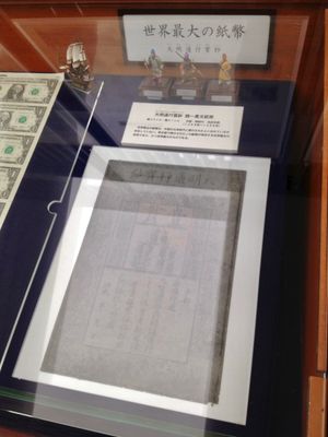 일본 나고야에 있는 도쿄-미쓰비시 UFJ 은행 화폐 박물관에 전시된 대명통행보초(大明通行寳鈔) 지폐. 현대 미국 달러 지폐와 비교한 크기에 주목할 수 있다.