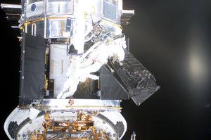 우주 왕복선 미션 STS-109의 NASA 우주 비행사들이 우주 유영 중 미광 천체 카메라를 제거하고 있다.