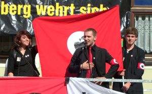 2007년 8월 18일 그래펜베르크 시장 광장에서 우익 극단주의 행진에 반대하는 시위의 일환으로, 풍자적으로 과장된 상징을 사용한 사과 전선 당원의 연설