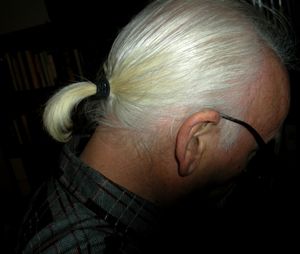 검은 배경에 흰 머리카락으로 된 남성의 말총머리