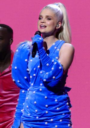 분홍색 배경에 파란 드레스를 입고 무대에서 공연하는 마거릿