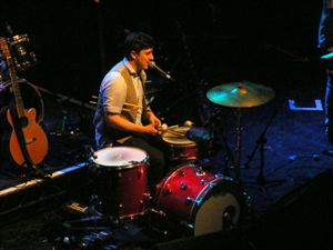 라이브 공연에서 밴드 멤버들은 여러 악기를 연주한다. 마커스 멈퍼드가 드럼 키트에 앉아 있다.