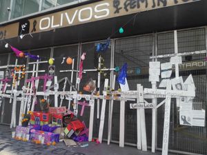Twenty-six crosses bearing the names of the deceased are displayed on the protective fence of Olivos station.