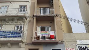 "집에 머무르세요" 라는 문구가 적힌 어린이들이 홍보하는 배너와 단체 및 정부가 홍보하는 몰타 국기