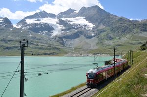 베르니나 익스프레스 열차가 오스피지오 베르니나 역 근처의 비앙코 호를 지나고 있다.