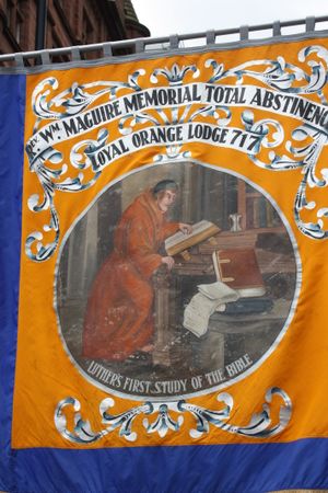 마르틴 루터가 아일랜드 그랜드 오렌지 로지의 배너에 있는 성경을 공부하고 있다.