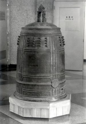 A black and white photo of a massive bronze bell on an indoor pedestal