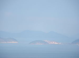 시사카섬 원경. 왼쪽에 묘진섬 남부, 중앙부에 네즈미섬과 이에노섬, 오른쪽에 미노섬 북부가 보인다. 이에노섬 북쪽 일부는 네즈미섬 뒤에 가려져 있다. 또한, 뒤편으로 우오지마가 보인다.