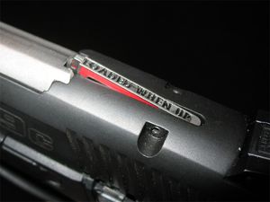 장전 표시기는 사수에게 촉각적이고 시각적인 경고를 제공한다. "Loaded When Up"이라는 문구가 있으며, 이 루거 SR9의 총기 마감 처리에 대해 빨간색이 두드러진다.