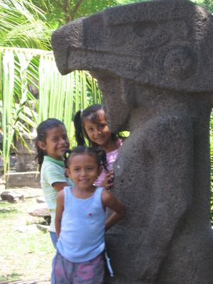 콜럼버스 이전 시대의 석상 옆에 서 있는 아이들