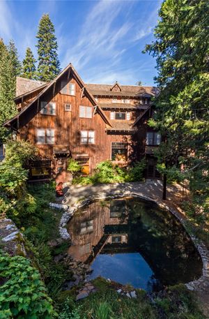 반사 수영장 뒤 숲에 나무 껍질로 덮인 소박한 다층 호텔이 있습니다.