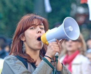 포르투갈 시위에서 소형 휴대용 전기 메가폰을 사용하는 여성. 전기 메가폰은 '반사' 또는 '재진입 혼'이라고 불리는 일종의 혼 스피커를 사용한다.