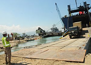  미국 육군 제7지원여단의 군인들이 아이티 포르토프랭스에서 통합 대응 작전을 위해 건설 차량 및 장비를 하역하고 있다.