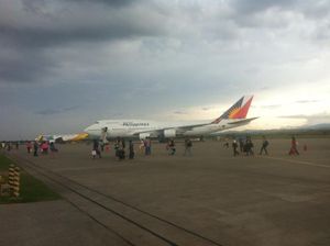 승객들이 필리핀 항공의 보잉 747-400과 세부퍼시픽의 에어버스 A320-200을 배경으로 제너럴산토스 국제공항 활주로에서 걷고 있다.