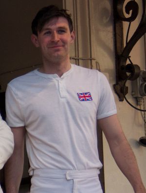 2012년 런던 올림픽 성화 봉송 중 연극 불의 전차의 해럴드 에이브러햄스 역할을 재현하는 맥아들