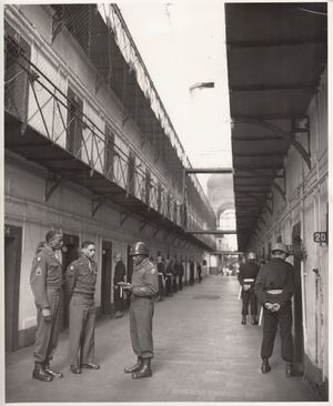 검은색 제복에 파란 헬멧과 흰색 벨트를 착용한 전 레지오나르들이 뉘른베르크 재판에서 주요 나치들을 경비하고 있다.