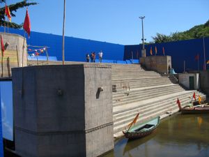 야외 세트의 파란색 스크린 앞에서 계단과 작은 배가 있다.