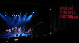 칼리어와 그의 밴드가 무대 위에서 찍은 사진으로, 옆에는 대형 매시브 어택 배너가 있다