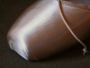 단단히 팽팽하게 당겨진 토슈즈의 새틴 외피는 내부의 토 박스 모양을 드러낸다.