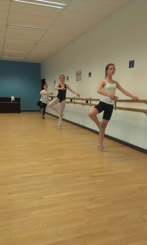 발레 슈즈를 신고, 듀미-포앙트 자세로 한 발로 서는 연습을 하는 아이들