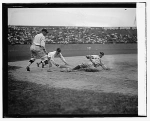 양키스 포수 월리 샹이 3루로 슬라이딩하고 있다. 세네터스의 3루수는 오시 블루지이며, 플레이를 지원하는 투수는 피르포 마베리이다.