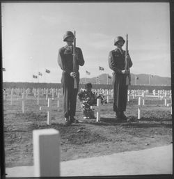 1951년 4월, 부산의 유엔군 묘지에서 한 한국 소녀가 미군 병사의 묘에 헌화하고 있으며, 의장대 군인들이 예를 표하고 있다.